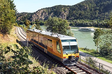 Goldener Triebwagen der Wachaubahn fährt entlang der Donau